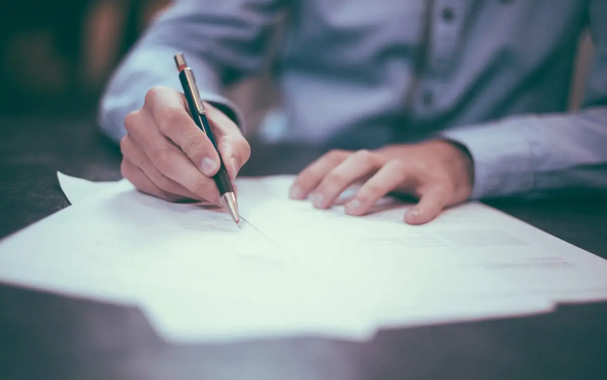 Manos firmando documentación administrativa sobre un escritorio