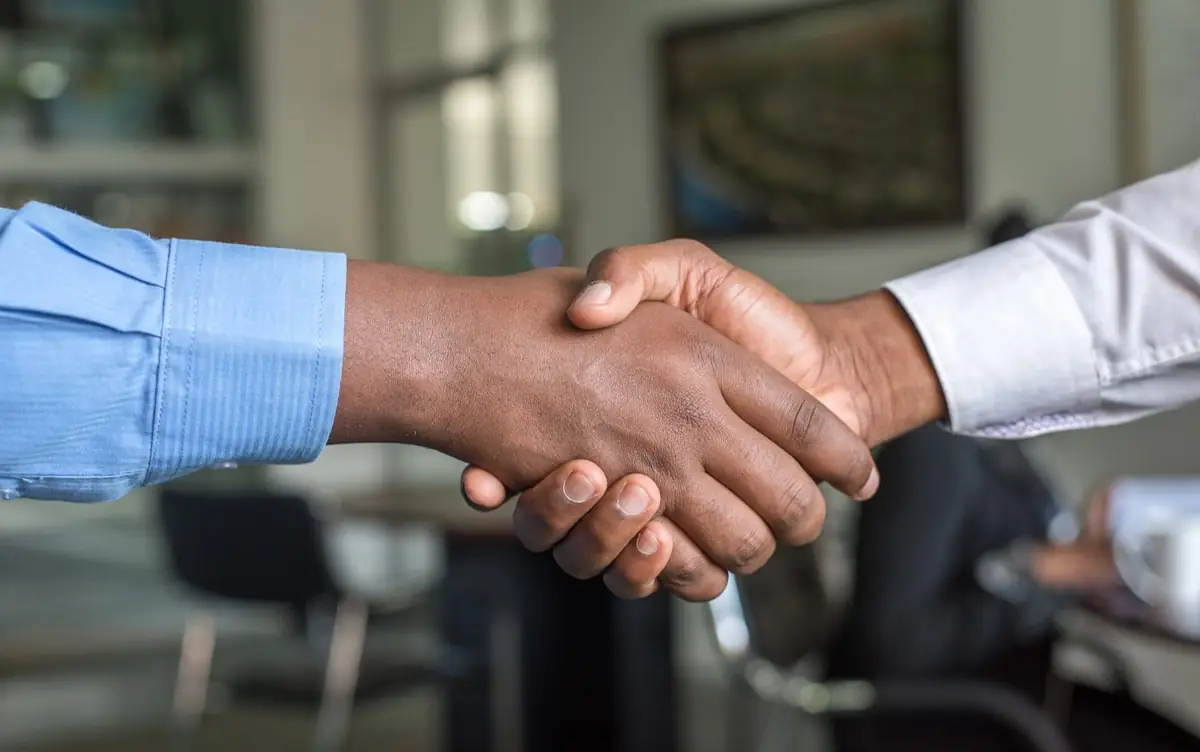 Saludo entre un ejecutivo y un coordinador durante una reunión de trabajo